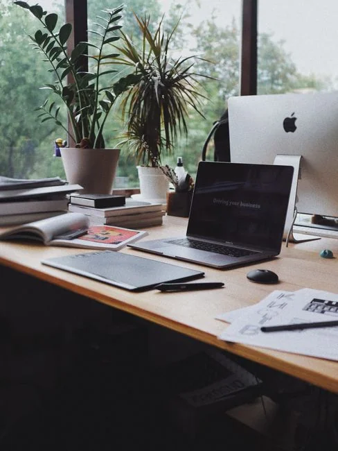 Un homme retouche l’image d’un fruit sur un MacBook Pro, assis dehors sur l’herbe.